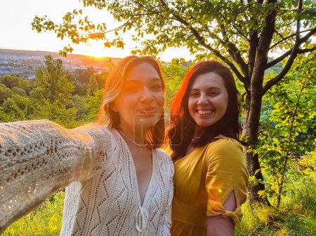 two pretty women take selfie at sunset