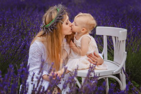 mother in lavender wreath kisses her daughter, who is sitting on white chair