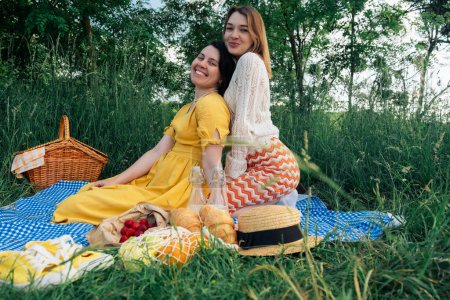 Two young women on blue blanket outdoors on a picnic