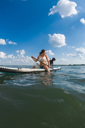 Foto de Mujer feliz con perro en supboard vacaciones de verano - Imagen libre de derechos