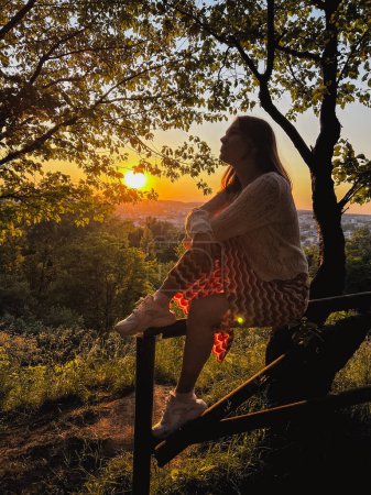 Réconfort coucher de soleil urbain : femme sur la clôture, embrassant la vue sur le paysage urbain