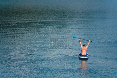 Mann auf Paddelbrett in der Mitte des Sees
