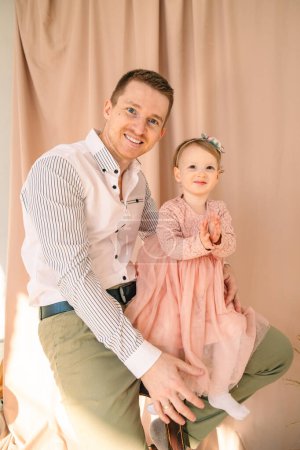 portrait of father with toddler daughter in studio