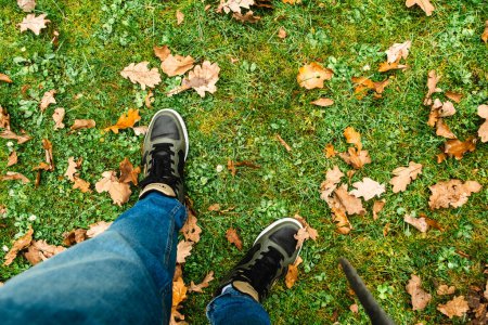 Téléchargez les photos : Hommes jambes debout sur le champ d'herbe recouvert de feuilles de chêne d'automne copier l'espace - en image libre de droit