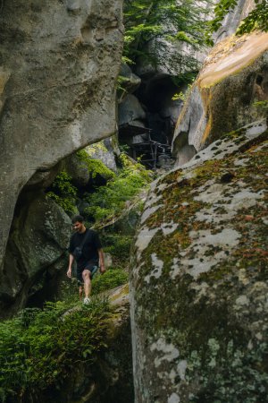 Téléchargez les photos : Homme randonnée touristique par les rochers sur l'espace de copie de forêt - en image libre de droit