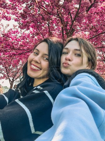 Téléchargez les photos : Deux petites amies heureuses prenant selfie sous sakura floraison arbre printemps temps - en image libre de droit