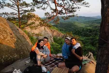 Téléchargez les photos : Amis heureux manger de la pizza à la falaise avec belle vue sur la montagne des Carpates - en image libre de droit