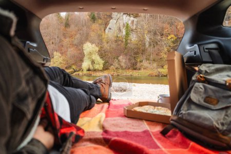 Téléchargez les photos : Couple assis dans le coffre de la voiture ayant pique-nique se reposant à la saison d'automne nature - en image libre de droit