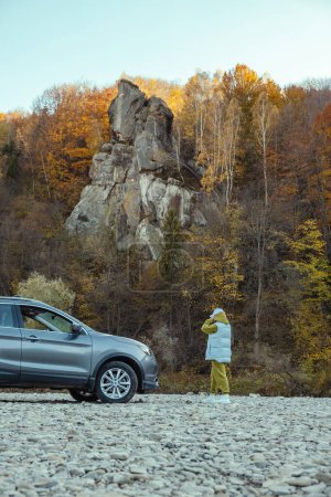 Téléchargez les photos : Femme voyageur près de voiture à la plage rocheuse de montagne rivière automne saison d'automne - en image libre de droit