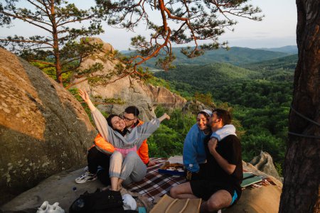 Téléchargez les photos : Amis heureux manger de la pizza à la falaise avec belle vue sur la montagne des Carpates - en image libre de droit