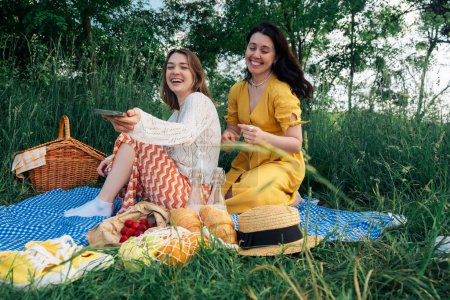 Two young women on blue blanket outdoors on a picnic