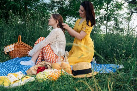 Two young women on a blue blanket outdoors on picnic