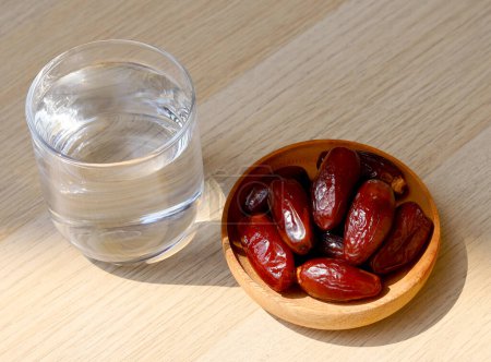 Foto de Ramadán iftar alimentos, frutas dátiles y agua de cristal od en la mesa de madera. - Imagen libre de derechos