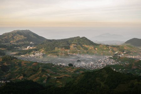 Téléchargez les photos : Vue aérienne du plateau de Dieng avec ville et entouré de collines. Vu de la montagne de Prau - en image libre de droit