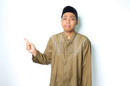 Photo for Sad asian moslem man pointing to beside isolated on white background - Royalty Free Image