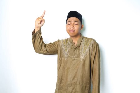 Photo for Sad asian moslem man pointing to above isolated on white background - Royalty Free Image