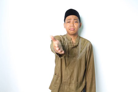 Photo for Asian muslim man reaching hand at camera to presenting with stressed expression isolated on white background - Royalty Free Image