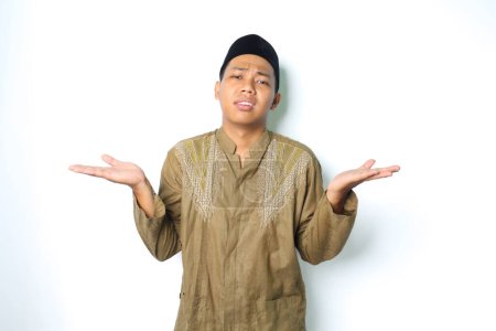 Photo for Stressed asian muslim man raising palm two side to presenting with confused expression isolated in white background - Royalty Free Image