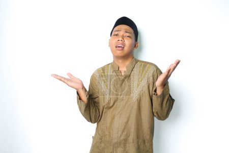 Photo for Stressed asian muslim man raising palm two side to presenting with confused expression isolated in white background - Royalty Free Image