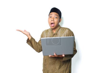 Photo for Shocked asian muslim man presenting empty space with holding laptop isolated on white background - Royalty Free Image