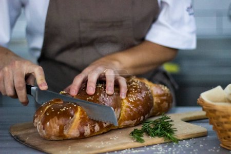 Foto de Chef cortando pan con un cuchillo y un sésamo negro - Imagen libre de derechos