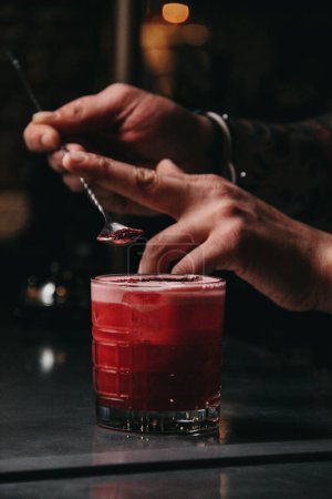 Foto de Camarero vertiendo cóctel con una copa de vino tinto en un mostrador de bar - Imagen libre de derechos