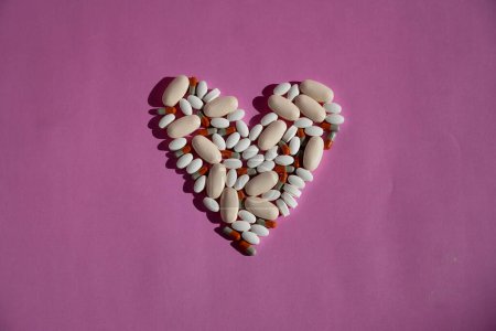 Photo for Heart-shaped medicines on a pink backdrop. - Royalty Free Image