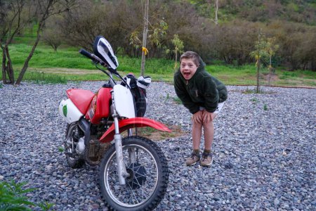Téléchargez les photos : Un enfant trisomique se tient à côté d'un vélo pour enfants, impatient de monter et de monter. - en image libre de droit