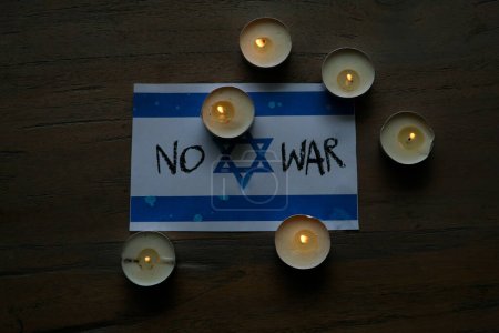 Téléchargez les photos : Le drapeau israélien est illuminé par la douce lueur des bougies allumées, créant une ambiance de révérence et de souvenir. - en image libre de droit