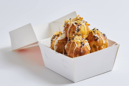 Takoyaki (bolas de pulpo) en una caja de comida para llevar o entrega, fondo blanco aislado