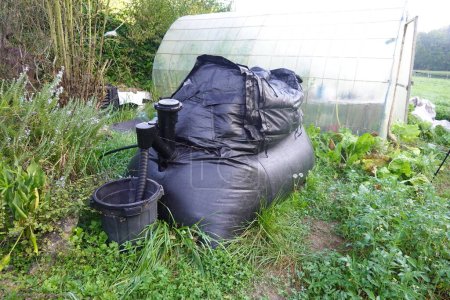 Téléchargez les photos : Biodigesteur dans le jardin. utilisations du biodigesteur dans la maison. accueil gaz produit par le biodigesteur biomasse de biogaz à la maison - en image libre de droit