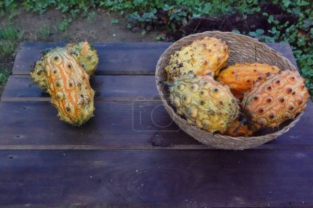 Photo for Kiwano harvest in a wicker basket on a wooden base. kiwano ready to eat. - Royalty Free Image