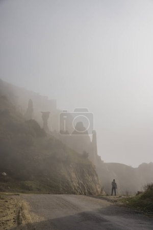 Foto de Región de Kuladocia, formada por restos volcánicos y erosión durante siglos, en el distrito de Kula de Manisa, donde una persona sola viaja en un día de niebla. - Imagen libre de derechos