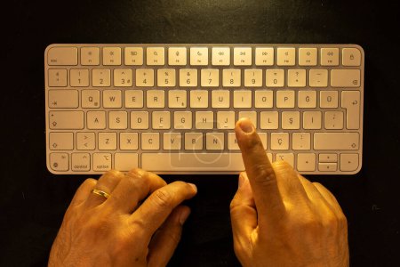 Téléchargez les photos : Mains masculines mariées sur clavier avec fond noir et prise de vue aérienne - en image libre de droit