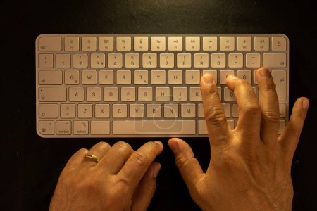Téléchargez les photos : Mains masculines mariées sur clavier avec fond noir et prise de vue aérienne - en image libre de droit