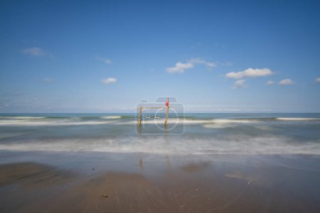Téléchargez les photos : Branche d'arbre et balancer parmi la mer et les vagues sur la plage avec un ciel bleu - en image libre de droit