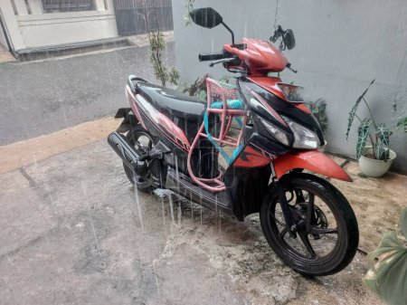 Téléchargez les photos : Une moto laissée exposée à la pluie dans le parking - en image libre de droit