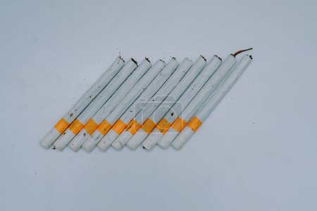 several kretek cigarettes lined up on a white base