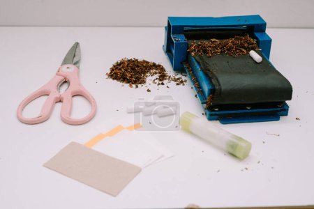 ein Zigarettenrollwerkzeug bestehend aus Pfeife, Schere, Papier und Papierleim