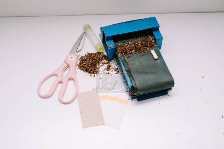 una herramienta para liar cigarrillos consistente en una pipa, tijeras, papel y pegamento de papel