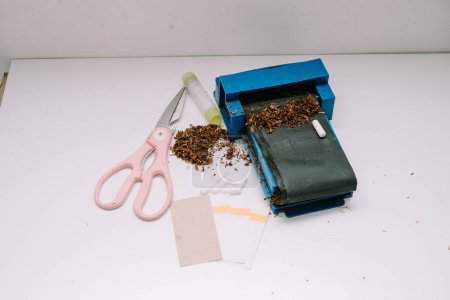 ein Zigarettenrollwerkzeug bestehend aus Pfeife, Schere, Papier und Papierleim