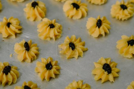 A syringe cake in the shape of a flower and filled with jam or raisins in the middle. Semprit cake is an Eid cake.