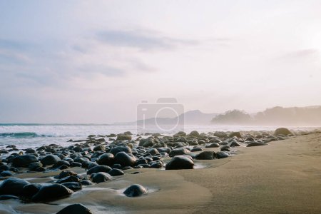 Morning tranquility captured in a serene coastal image, featuring small waves, rocky beach, and the calming aura of dawn