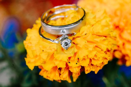 Photo for A wedding ring delicately placed atop vibrant yellow marigold petals, symbolizing the union of love and the blossoming journey ahead - Royalty Free Image