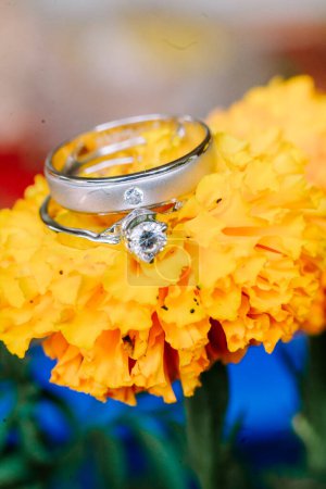 Photo for A wedding ring delicately placed atop vibrant yellow marigold petals, symbolizing the union of love and the blossoming journey ahead - Royalty Free Image