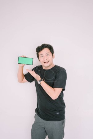 Un homme tient un téléphone écran vert, le pointant vers la caméra