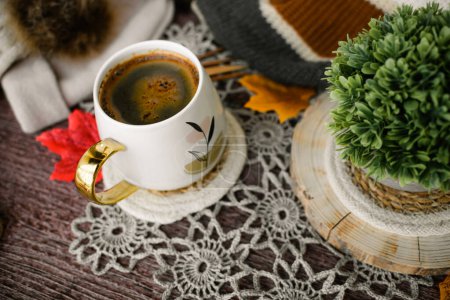 Taza de café con hojas de otoño y bufanda de punto sobre fondo de madera