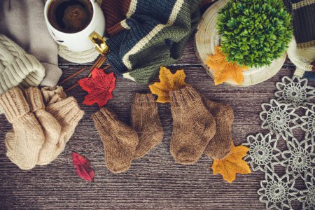 Tasse Kaffee mit Herbstblättern und gestricktem Schal auf Holzgrund
