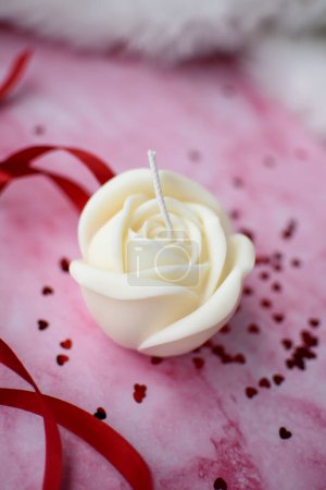 Téléchargez les photos : Mignonne bougie de cire de soja en forme de rose sur fond rose - en image libre de droit