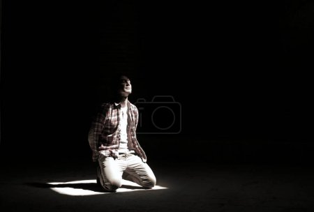 Junger Mann kniet in einem Lichtstrahl in einer Moschee in Teheran, Iran